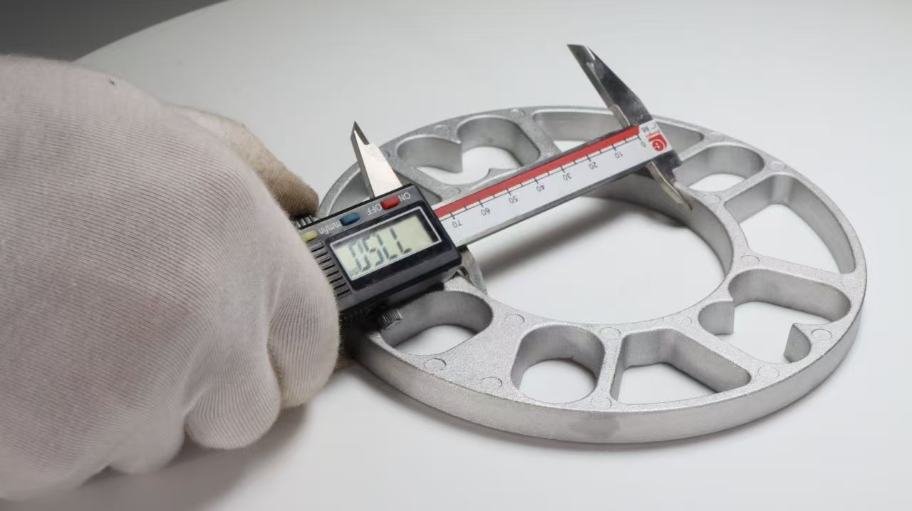 Technician measuring the center opening of a wheel spacer with a digital caliper