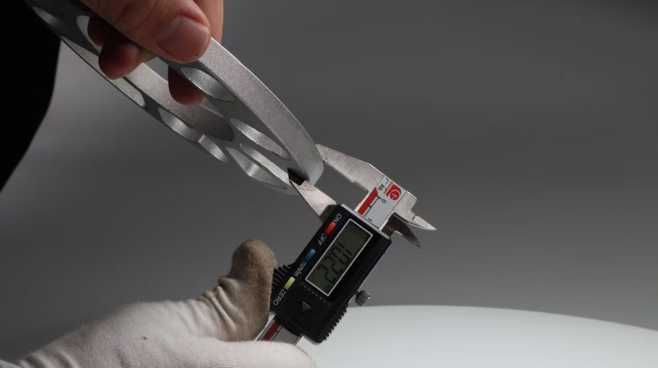 Technician measuring wheel spacer thickness with a digital caliper